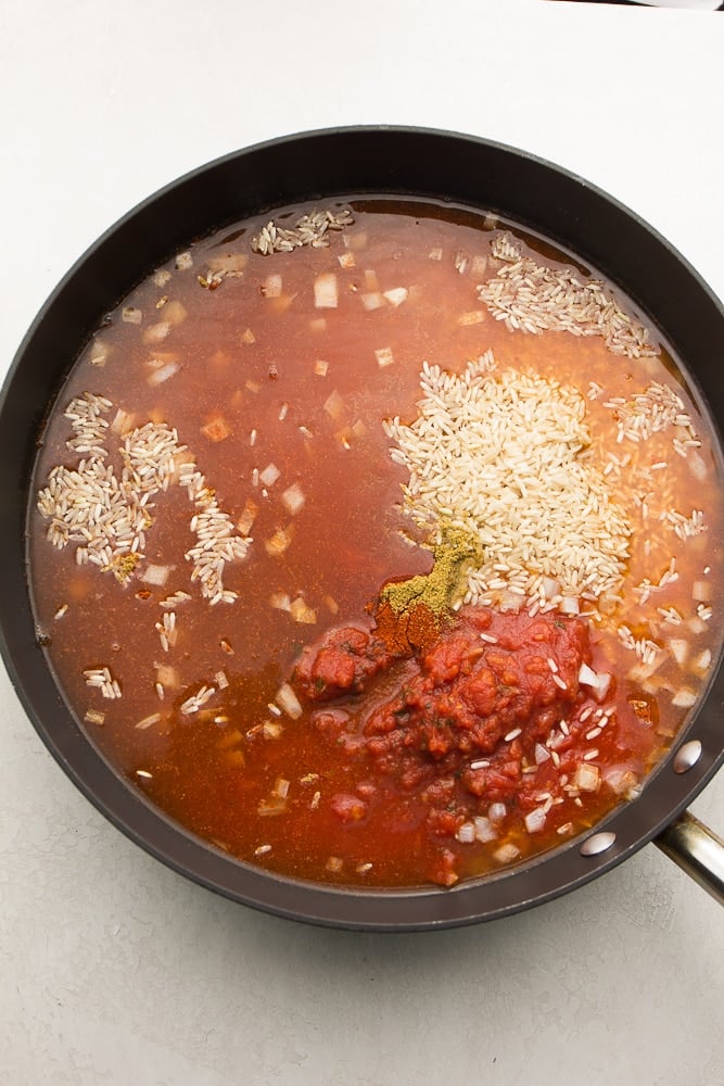 rice, tomatoes and other ingredients in a pan, not mixed up