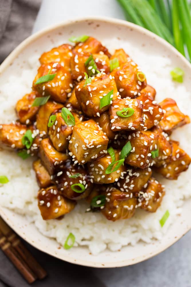 close up of a lot of sesame tofu in a bowl on top of rice