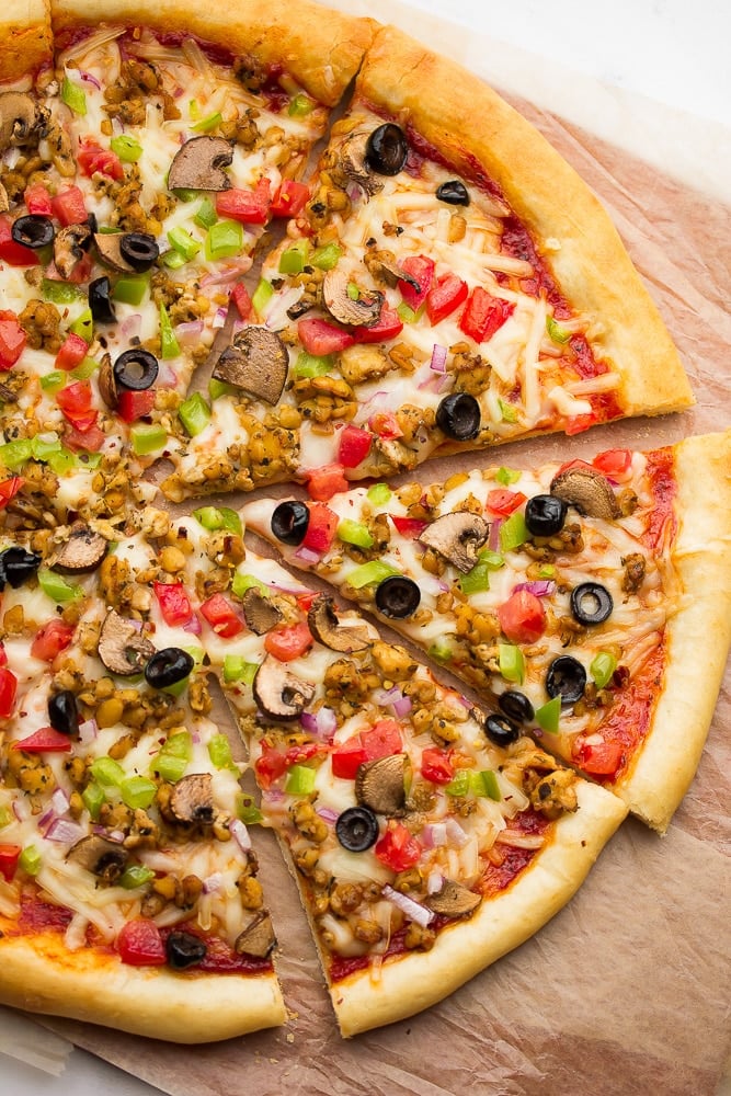 Cooked pizza with veggies, cheese, tempeh sausage, and tomato sauce