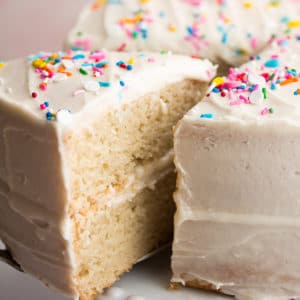 Close up of a slice of vanilla cake with sprinkles on top being removed