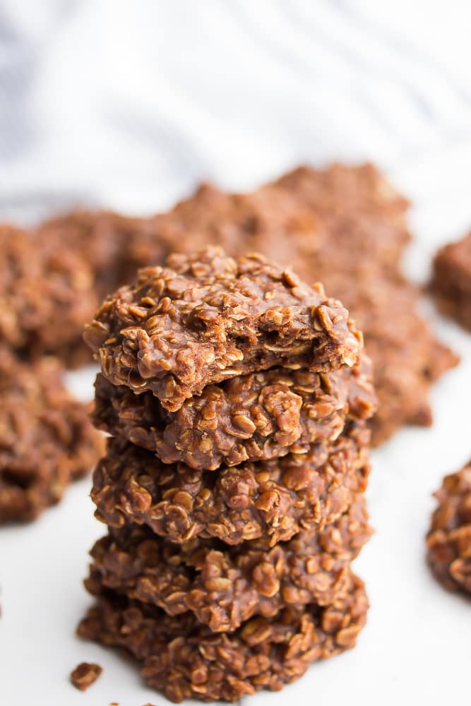 Close up of 5 vegan no bake cookies stacked on top of each other with a bite out of 1 cookie