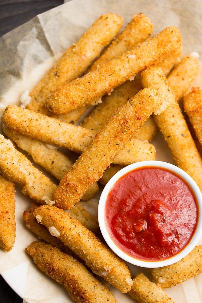 a bunch of fried mozzarella sticks with marinara dipping sauce