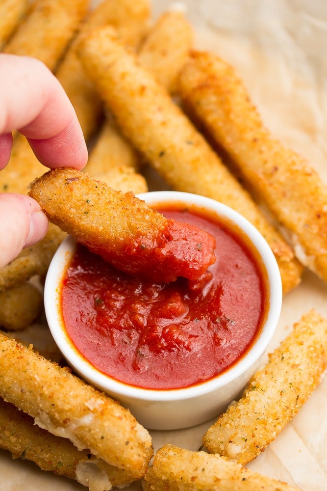 vegan mozzarella stick being dipped into marinara