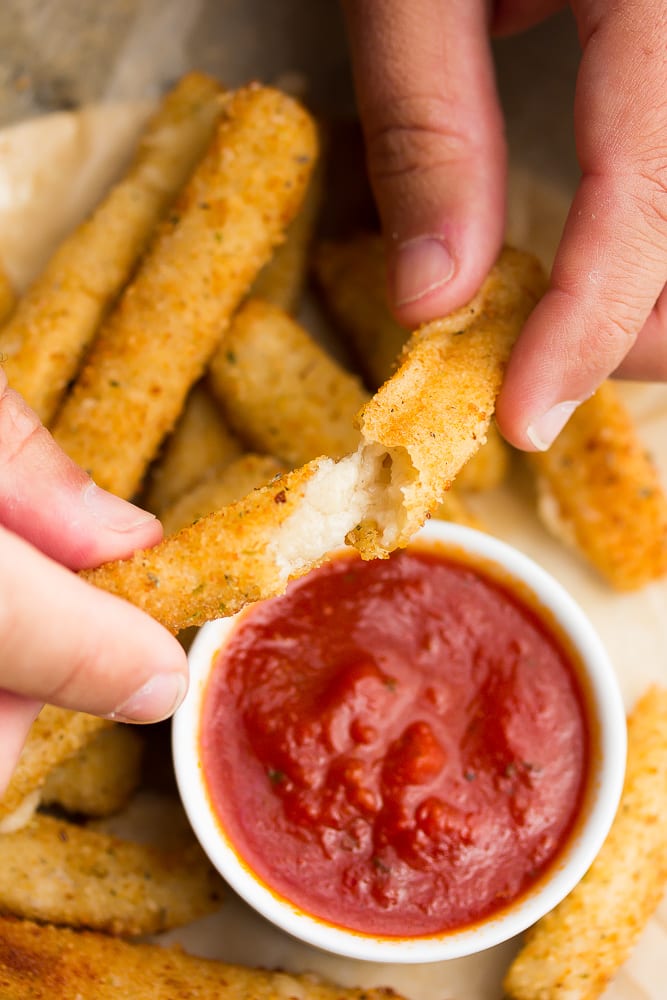 hands holding a fried cheese stick pulling it apart