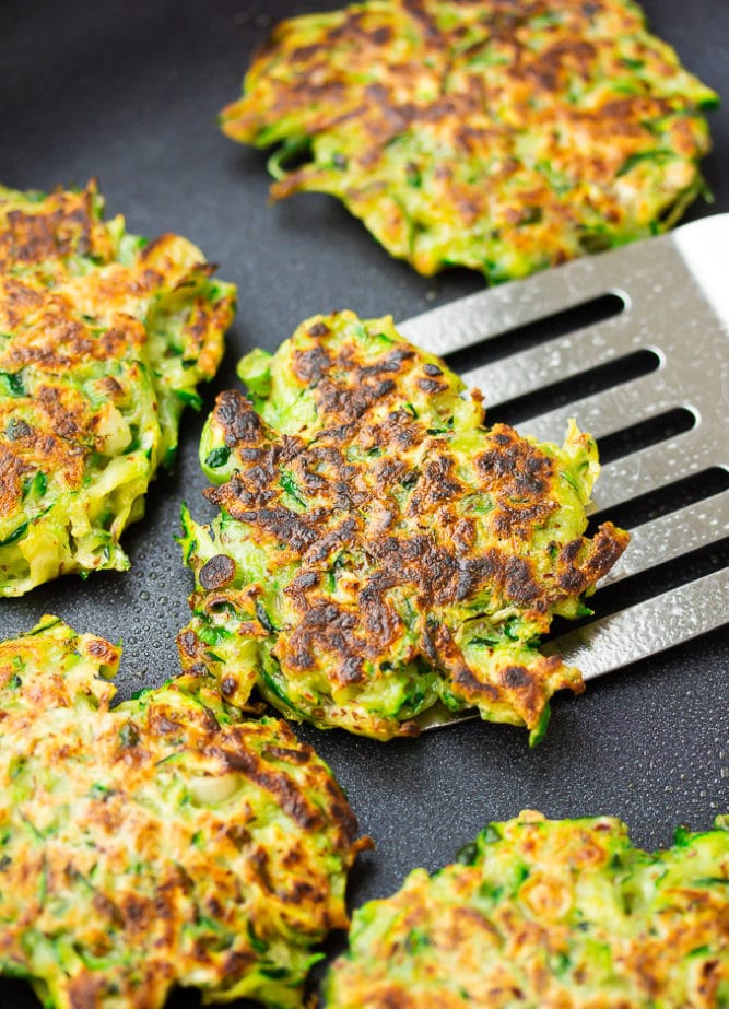 pan with fritters being cooked and lifted out with a spatula