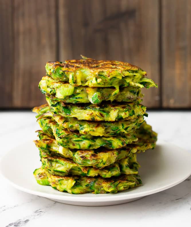 stack of vegan zucchini fritters on a white plate