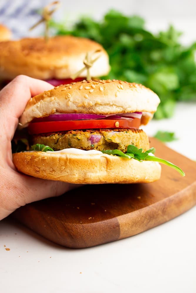 hand holding a burger with more in background