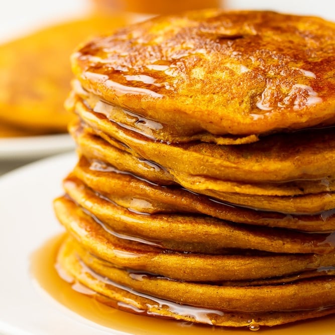 square image of stack of pumpkin pancakes on white plate