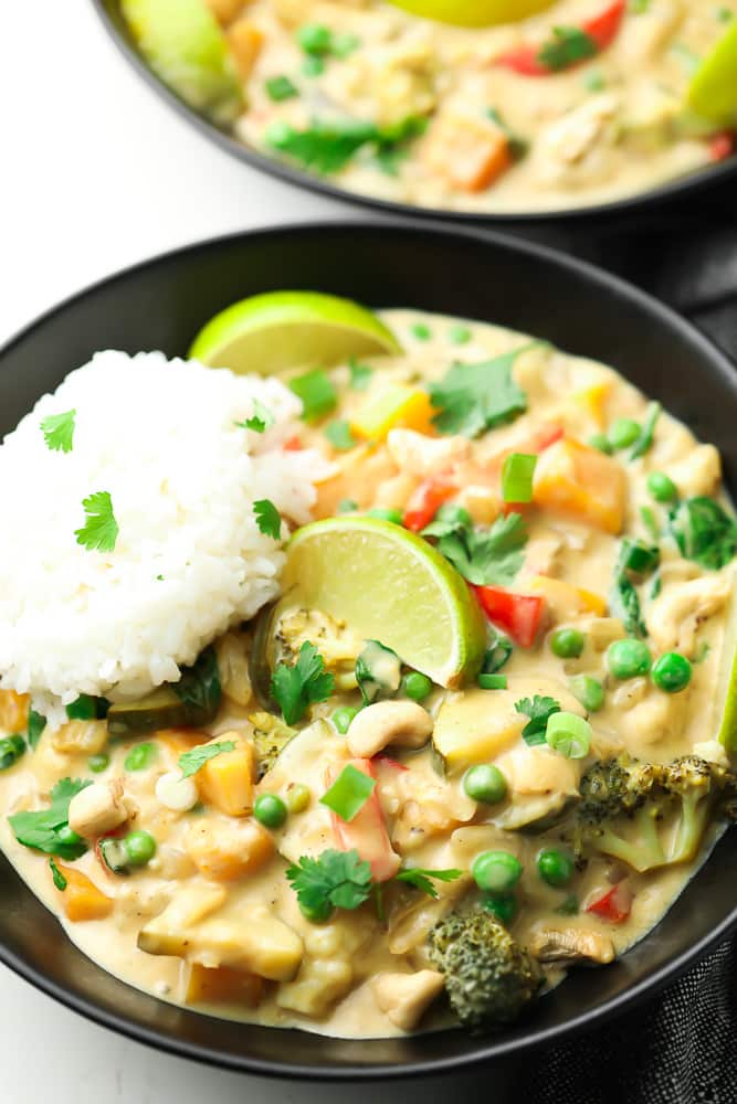 black bowl with white rice, creamy curry and limes