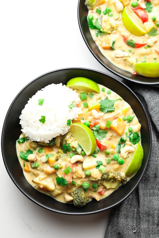 two bowls of thai green curry with rice on top