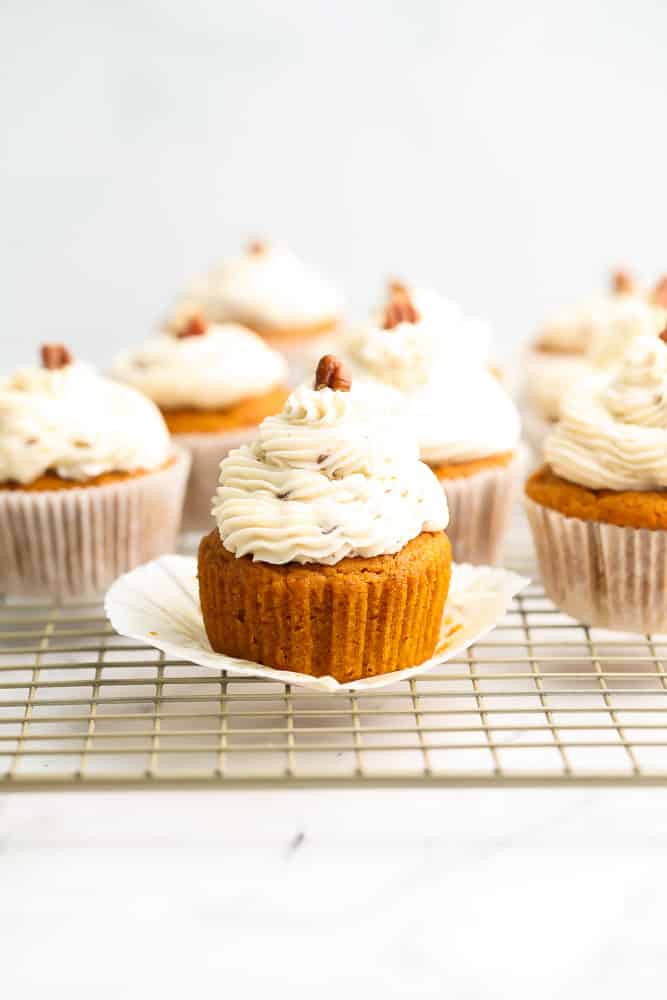 lots of pumpkin cupcakes with pecan pieces on top