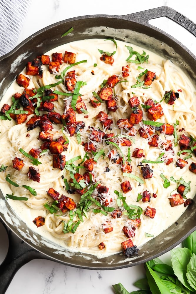 looking down on a pan full of creamy pasta with basil and tofu pancetta