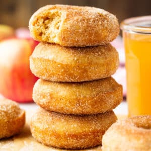 square image of stack of donuts, cider in background