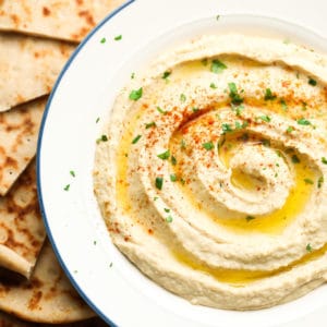 bowl of hummus with olive oil and paprika, bread around it