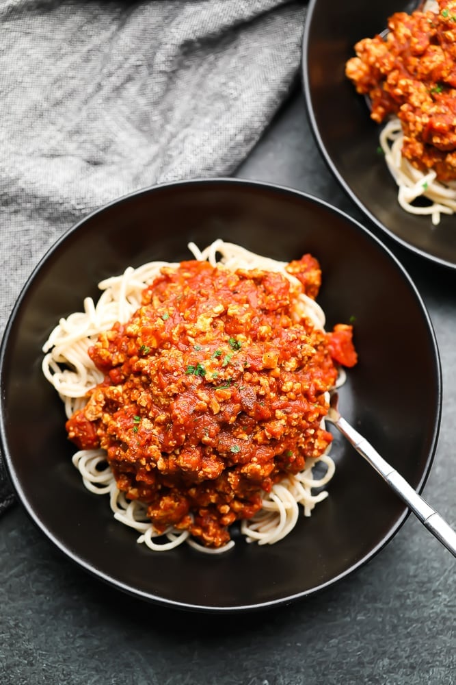 vegan bolognese sauce in black bowl over pasta