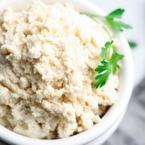 square image of vegan ricotta cheese in bowl with sprigs of parsley