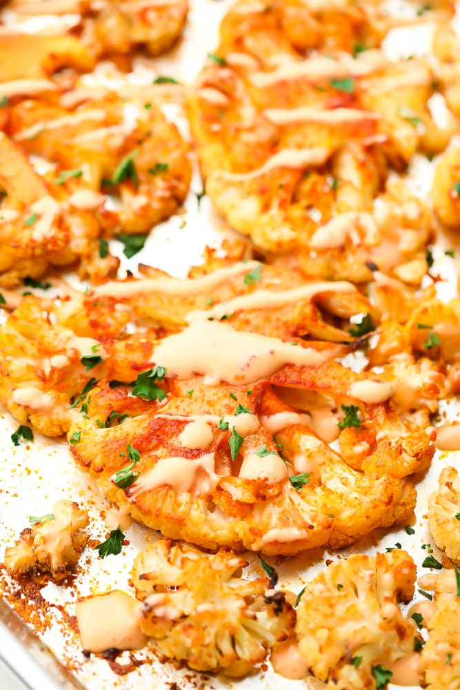 close up of cauliflower steak with creamy sauce on a silver pan