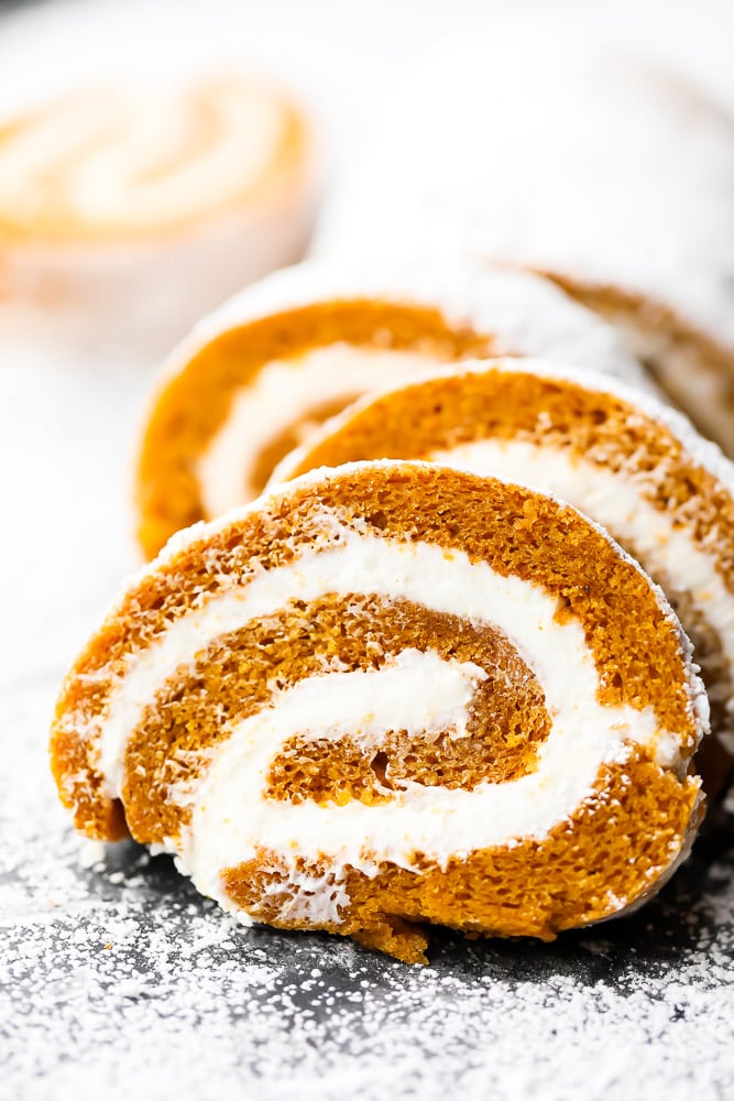 slices of pumpkin roll cake with powdered sugar all around