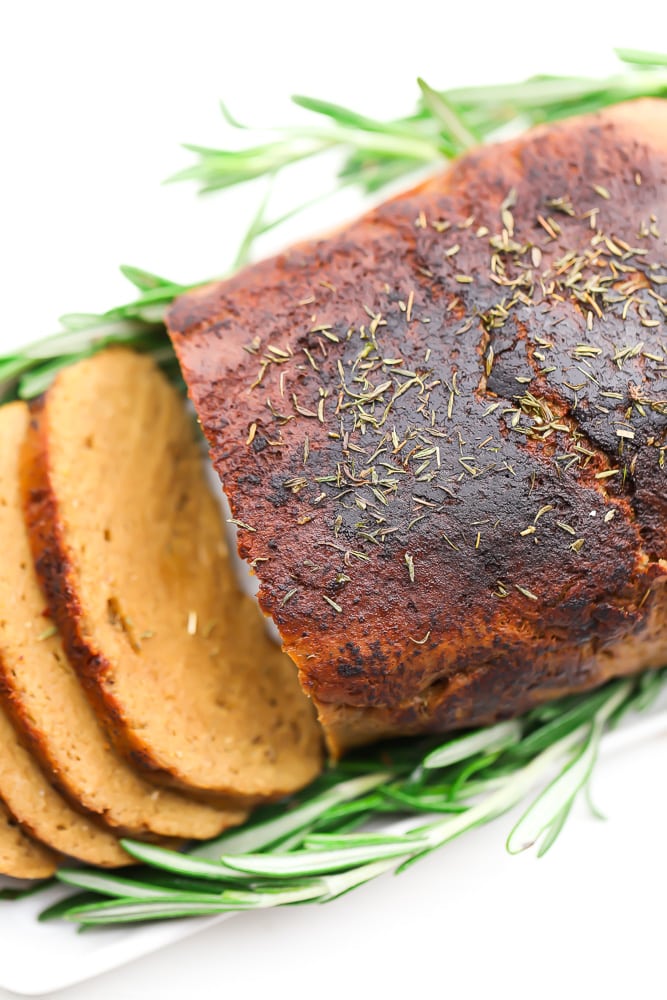 looking down on a vegetarian turkey loaf, partially sliced with sage around it