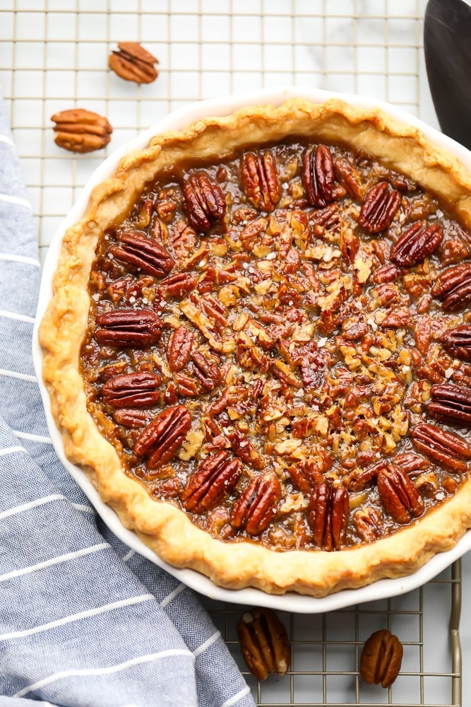 whole cooked pecan pie with blue towel on a cooling rack