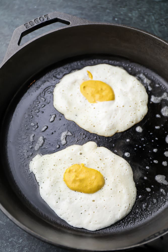 uncooked white fried eggs in a pan with a yolk