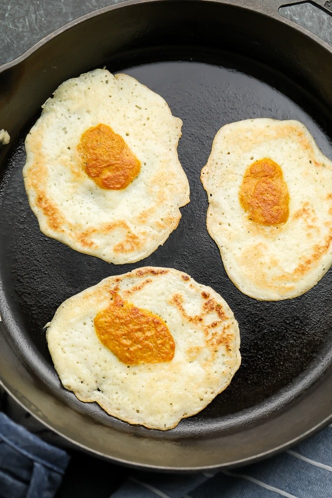 looking down on three eggs in a cast iron pan