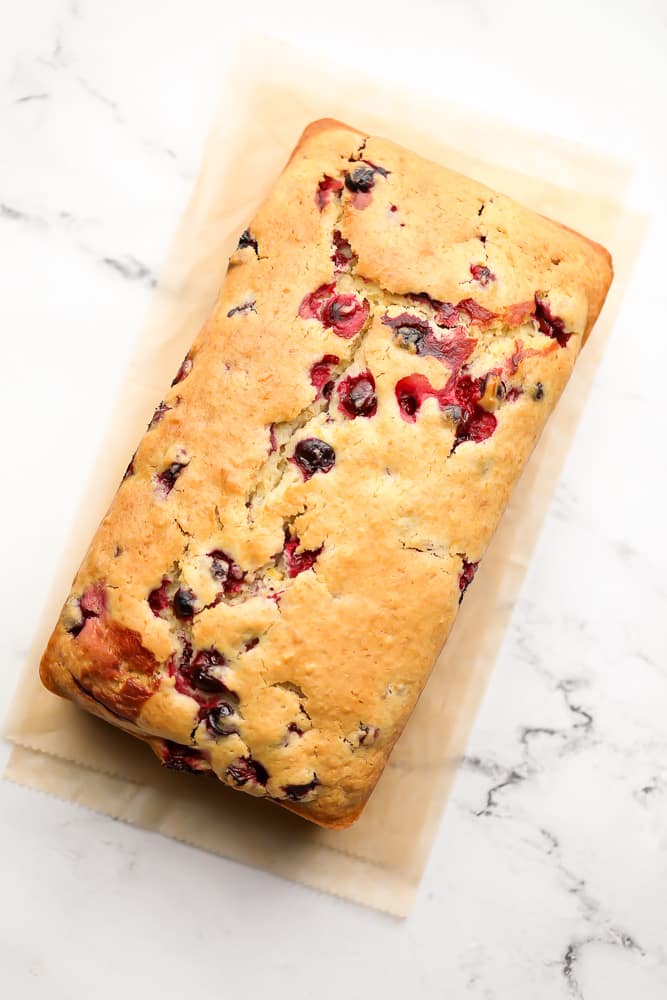 cooked orange loaf with cranberries, on marble backdrop