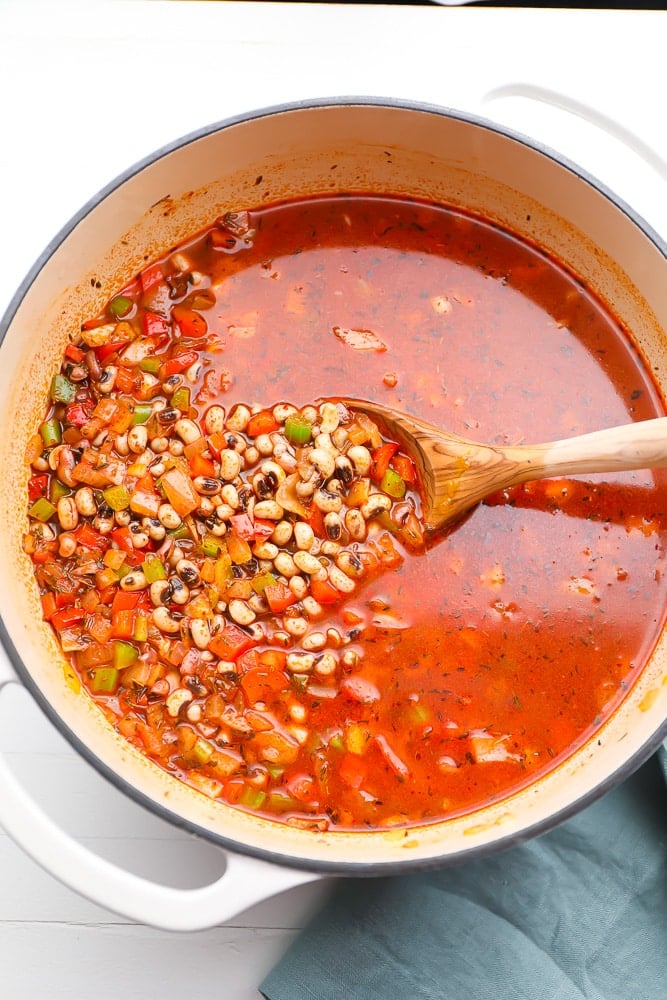 beans not yet cooked in a pot with red broth