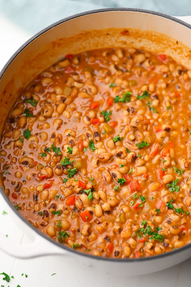 white pot of beans with veggies, light brown in color