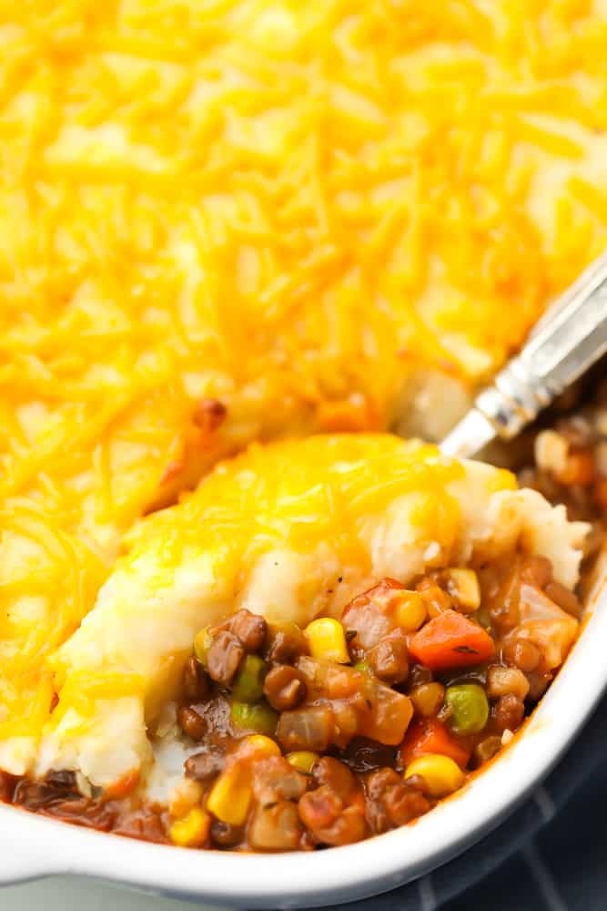 casserole dish with lentil shepherd's pie and a spoon serving it