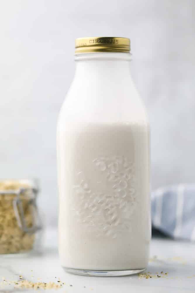 large jar of hemp milk with hemp seeds in background, grey in back