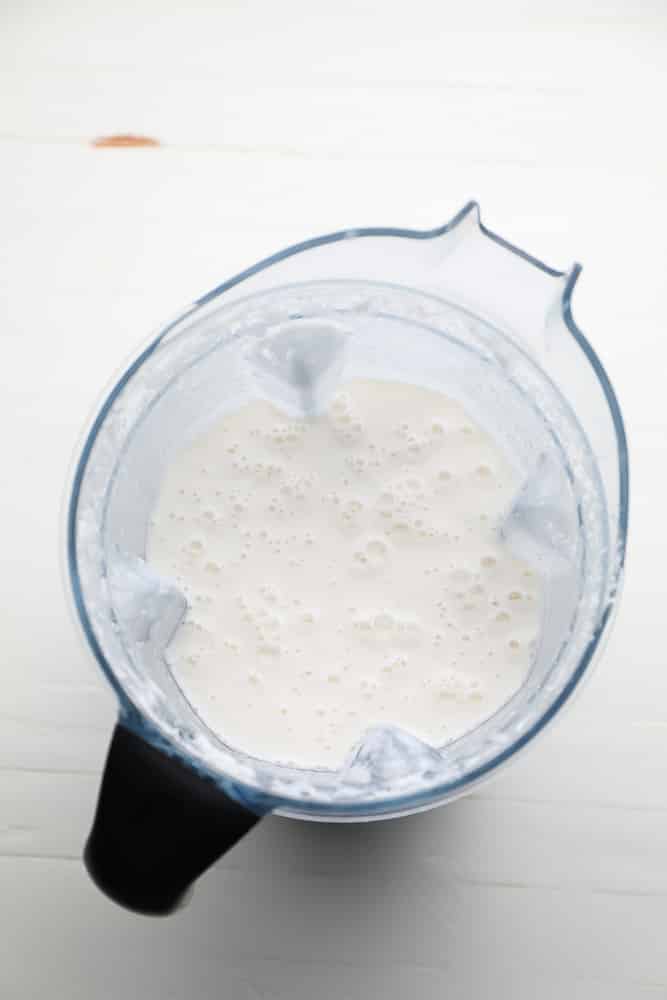 blender full of creamy mixture with bubbles on top