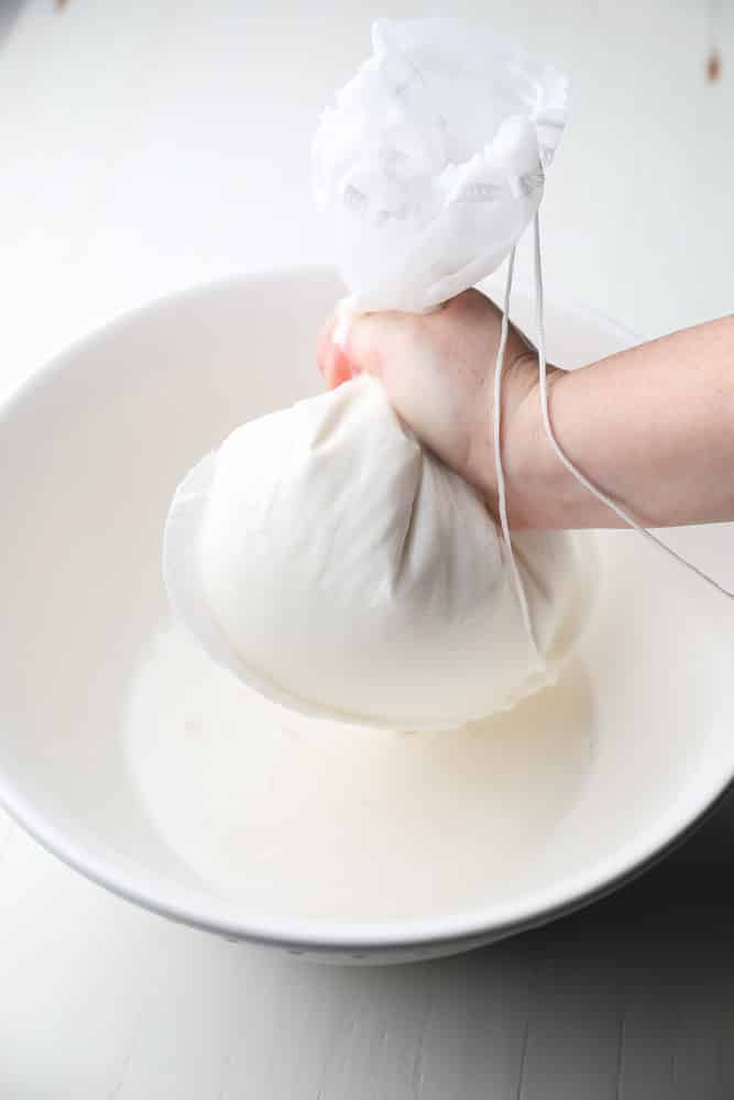 coconut milk being squeezed through a nut milk bag