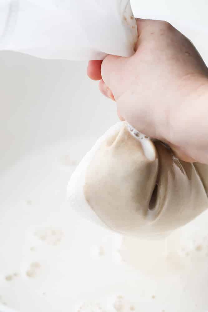 squeezing white milk out of a nut bag