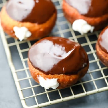square image of boston cream donuts on rack
