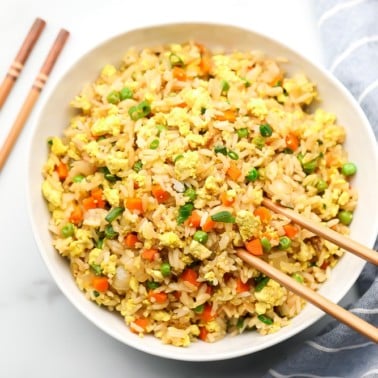 square image of a bowl of rice with veggies in it and chopsticks