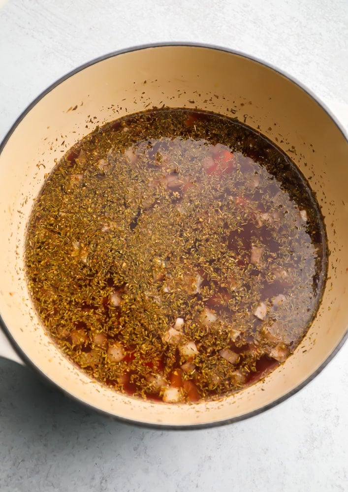 Cooking vegetable broth, vegetables, and herbs in a large pot