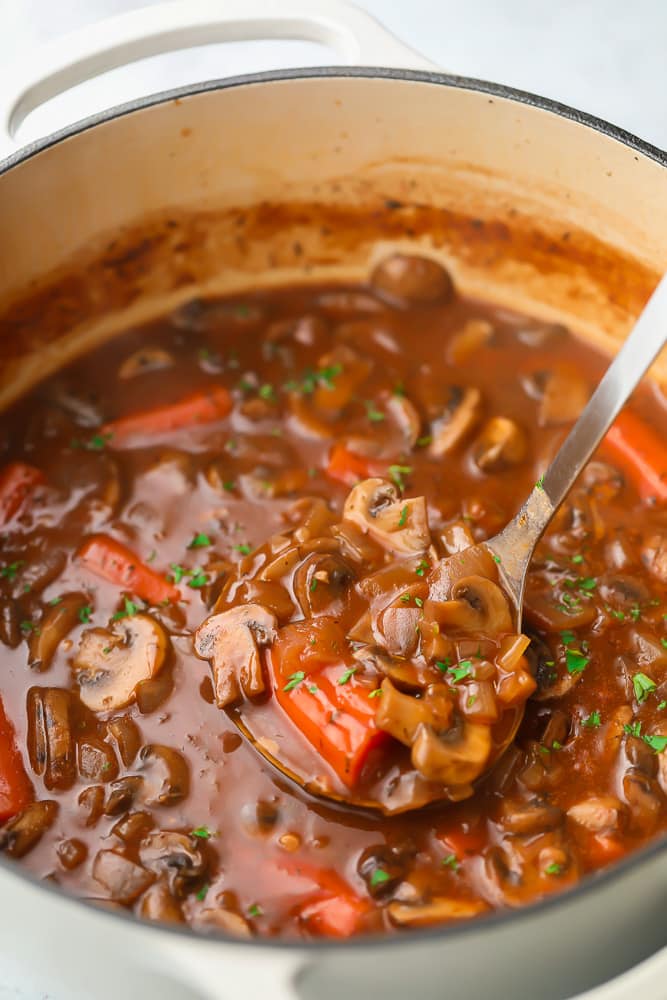 Ladling a scoop of mushroom bourguignon out of a pot