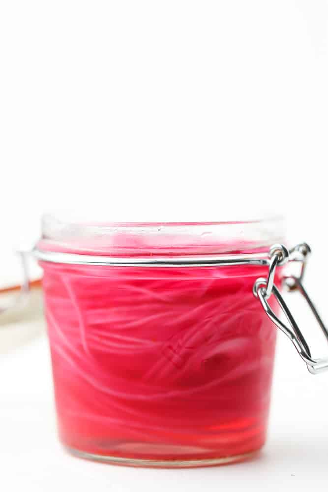 sliced red onions in a sealed mason jar