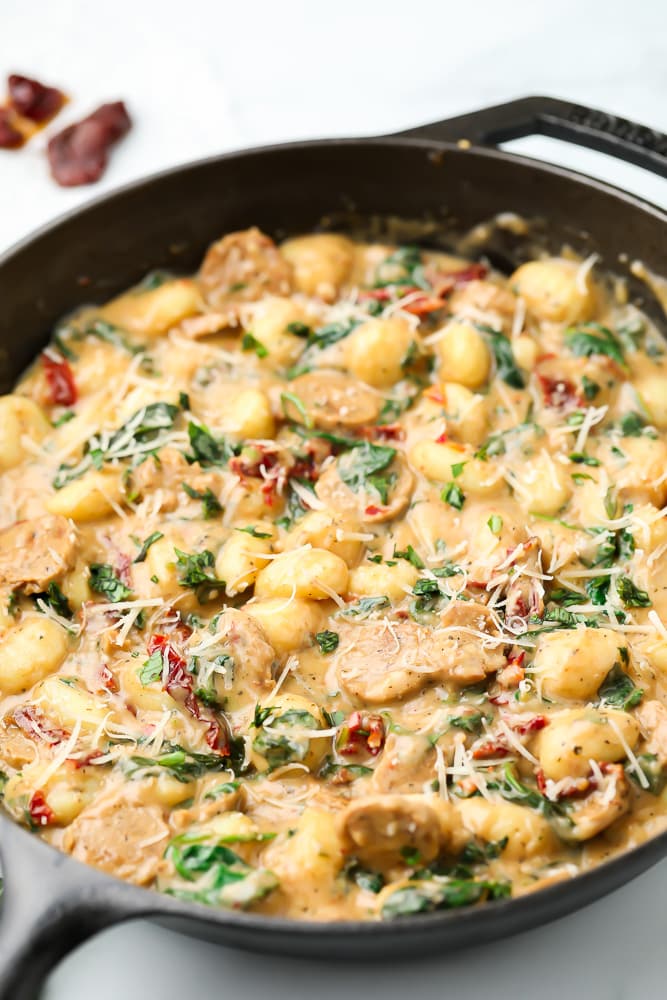 cast iron pan from side with gnocchi and  vegan sausage