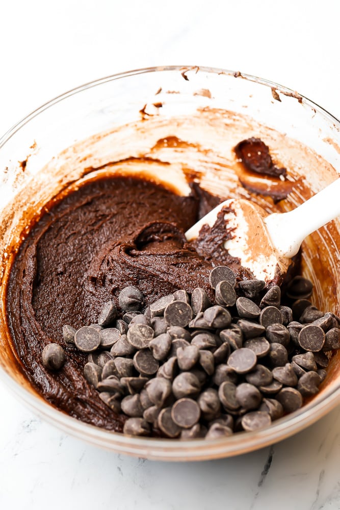 bowl of brownie batter with chocolate chips and a white spatula