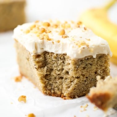 square image of a piece of cake with frosting and walnuts on top