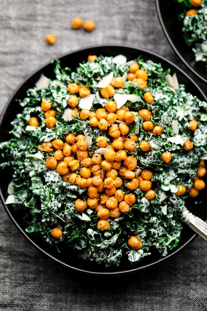 close up of salad in a black bowl topped with chickpea croutons