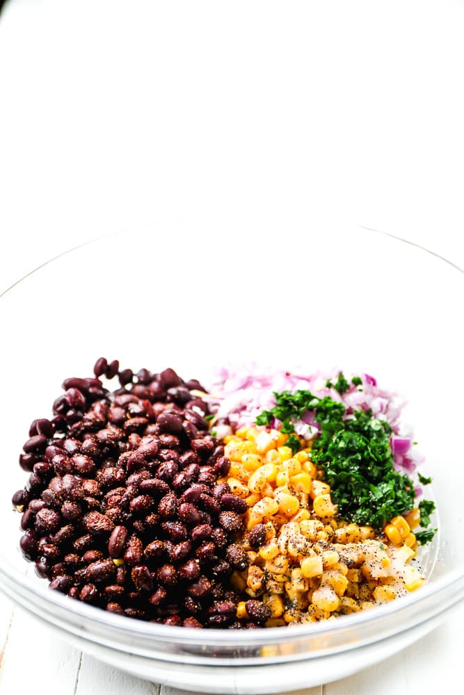 black beans, corn, herbs, and onions in a glass bowl