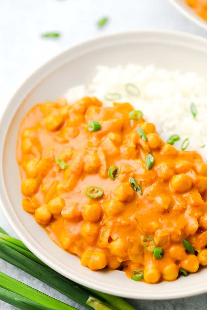 close up up bowl with beans in orange curry sauce and rice