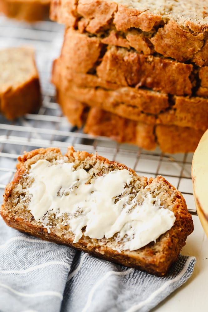 slice of banana bread with butter next to a sliced loaf