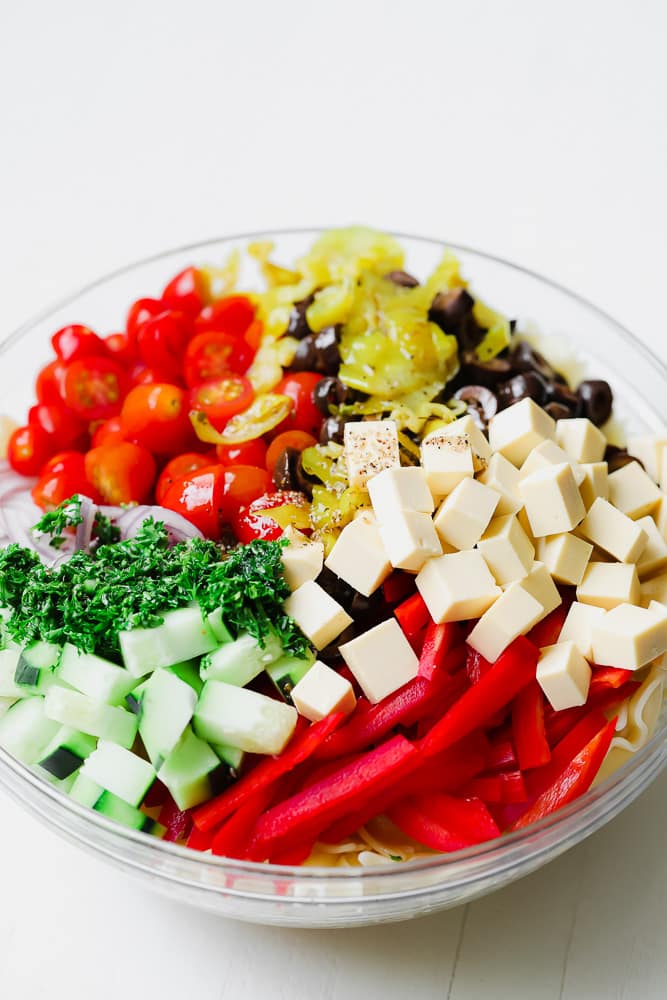 chopped veggies and vegan cheese in a glass bowl