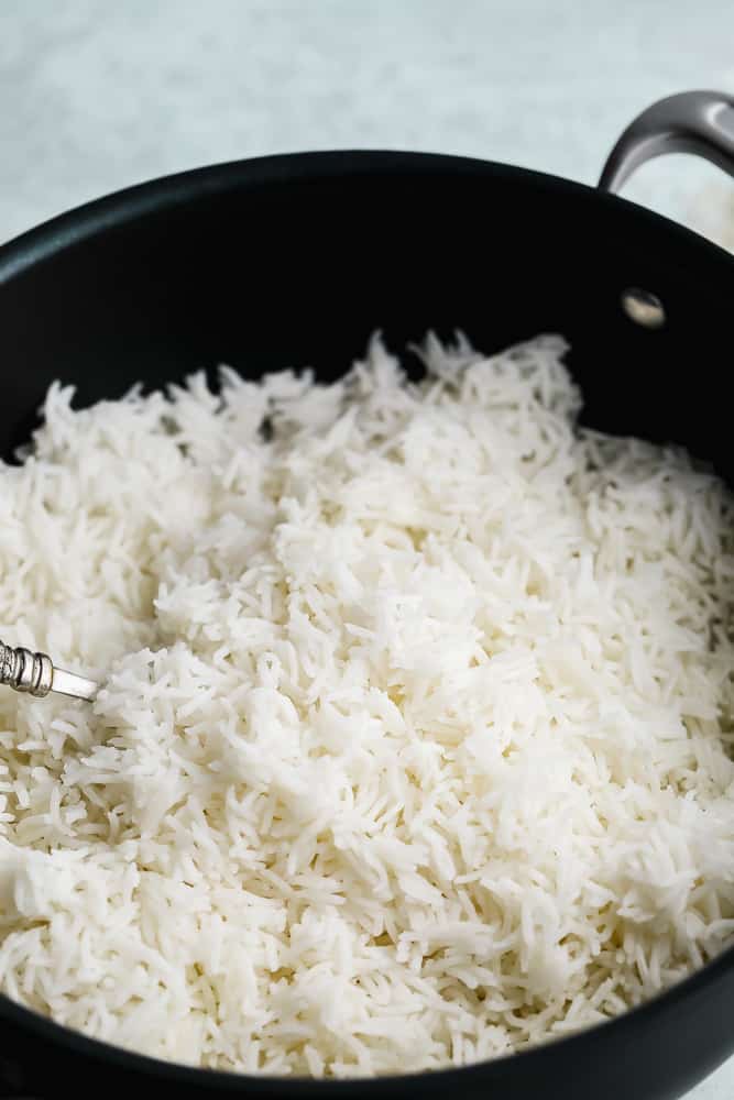 close up on a fork fluffing white rice in a black pot