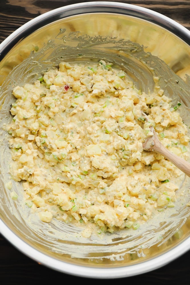 silver bowl with wooden spoon and potato creamy mixture being stirred