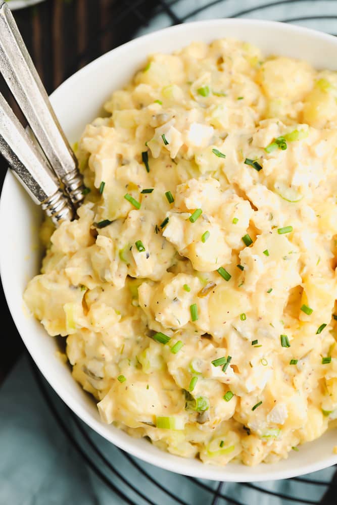 close up of vegan potato salad with forks and blue towel in background